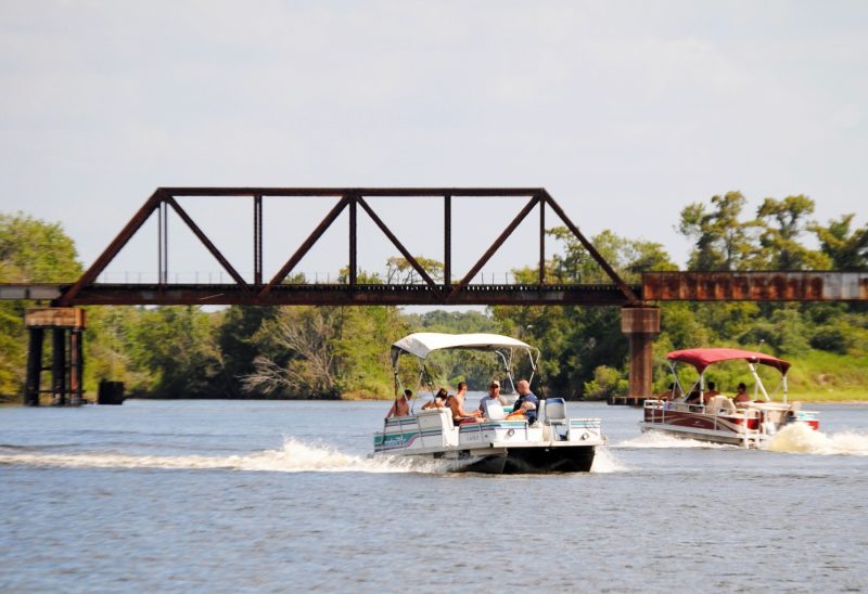 two pontoon boats rentals cruising under a bridge