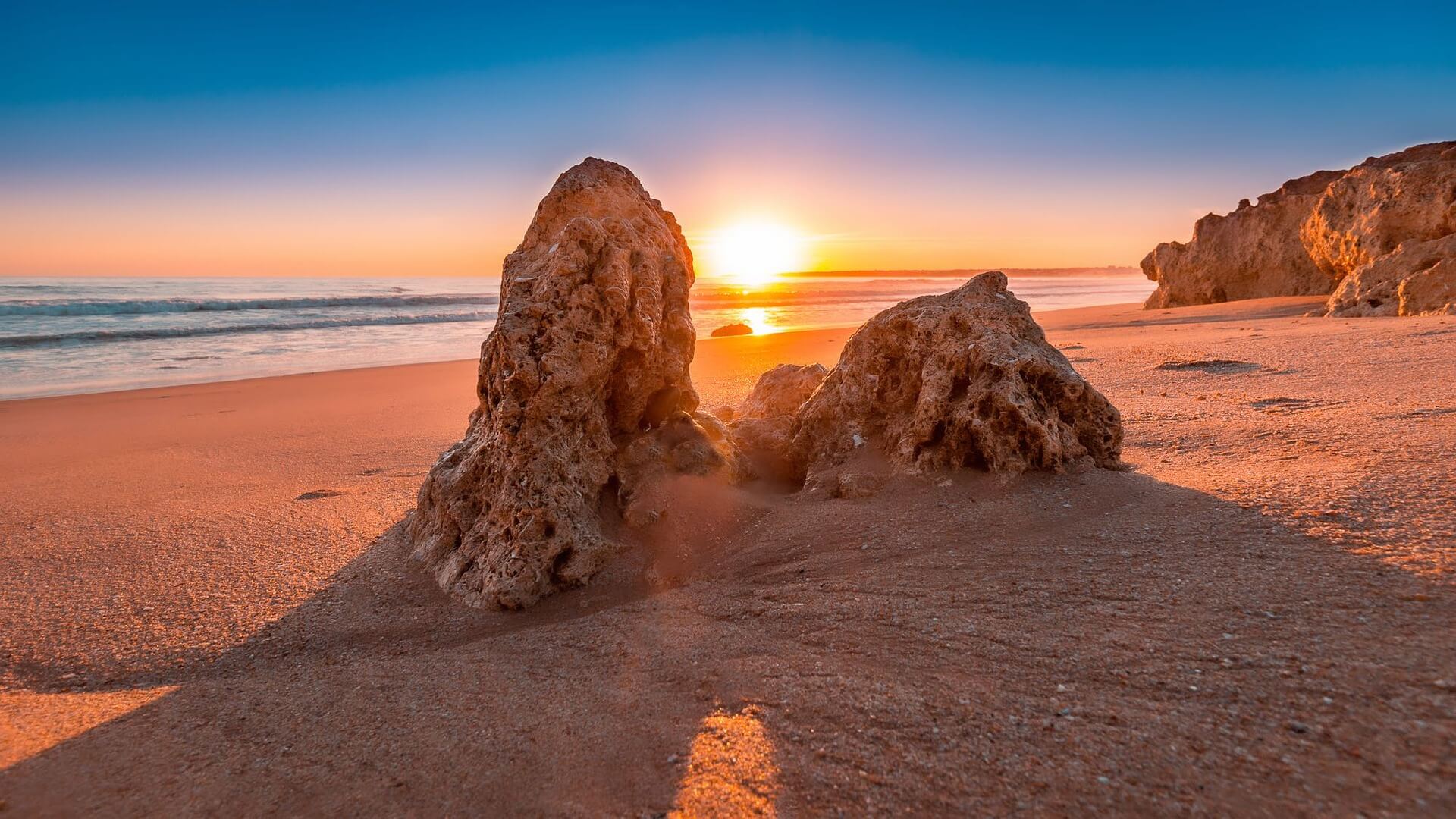 Sonnenstrahlen durch Felsen am Strand in Portugal