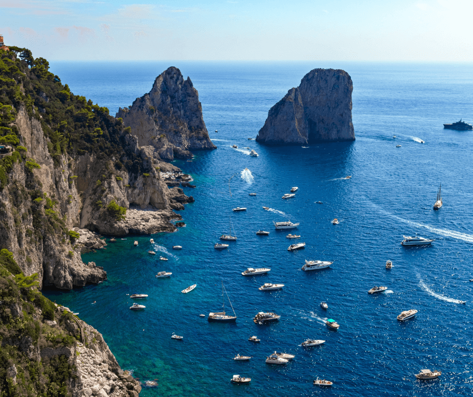 Motorboote und Segelyachten, die in einer Bucht vor Capri ankern oder herumfahren 