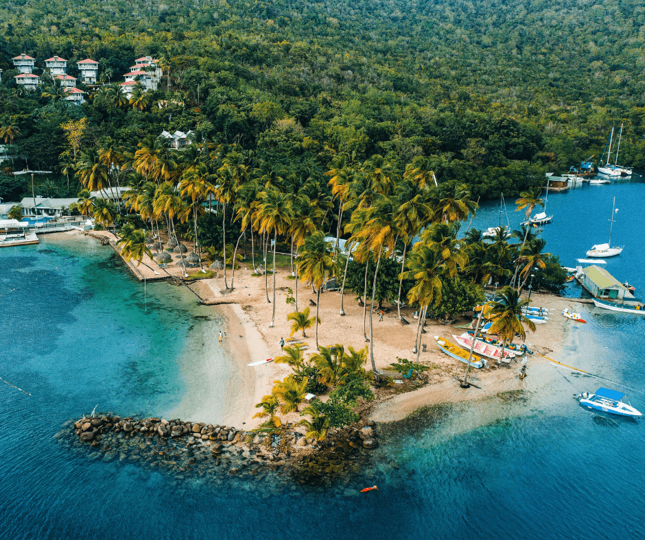 Küste von St. Lucia bewachsen mit grünen Palmen und Booten vor Anker im blauen Wasser