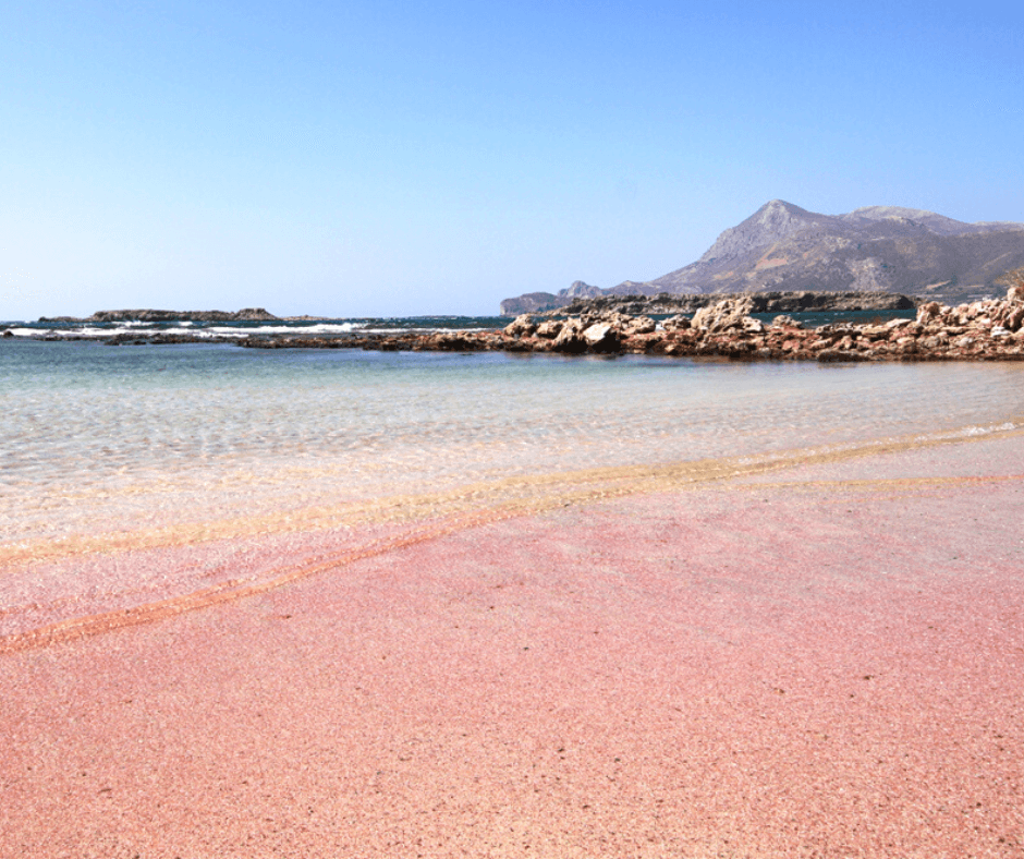 Pinker Strand Falasarna, Kreta - Pinker Sand und türkisblaues Wasser mti Hügelandschaft im Hintergrund