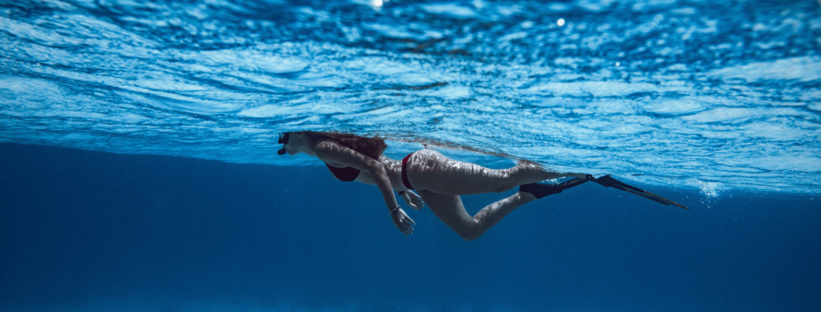 Frau, die im Bikini im blauen Wasser schnorchelt