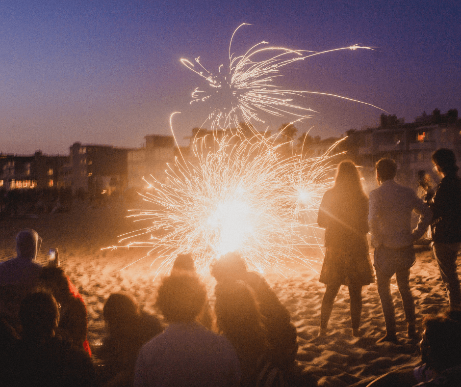 Feuerwerk am Strand mit verschiedenen Personen, die im Sand sitzen oder stehen