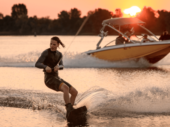 Boot mieten für einen Tag, Motorboot und Wakeboarder auf dem Wasser bei Sonnenuntergang
