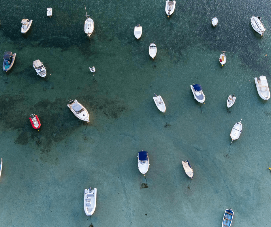 Von oben betrachtet sind Boote im klaren Wasser vor Ibiza verankert.
