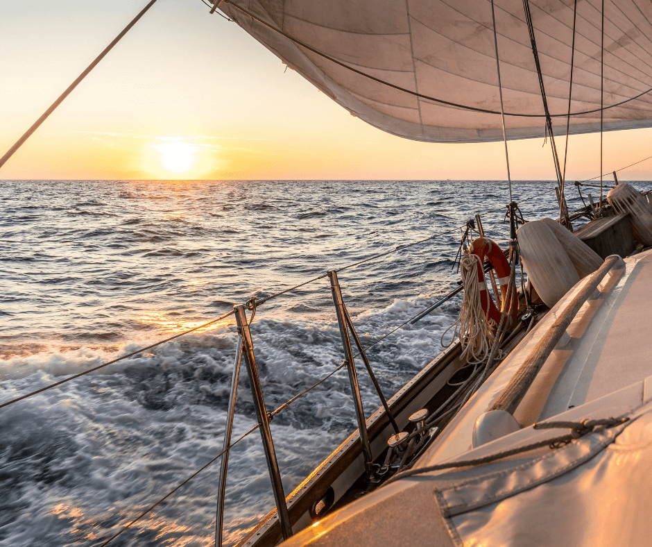 Segelboot auf dem Meer und im Hintergrund Sonnenuntergang während eines Segelurlaubs. 