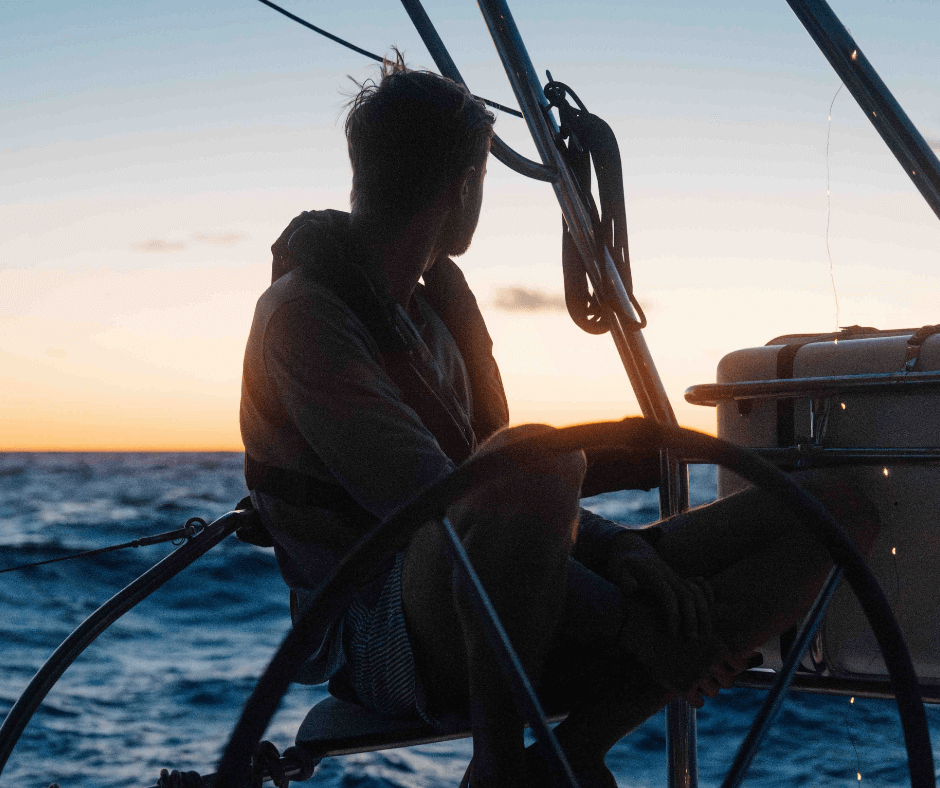 Eine Person und ein Sonnenuntergang sind im Hintergrund zu sehen. Auf dem Segelboot bei der Vorbereitung der Pazifiküberquerung. 