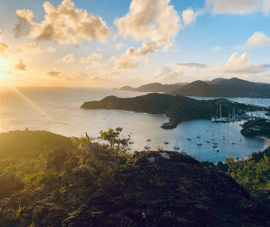 Eine Bucht in Barbuda und Antigua. Man sieht viele Schiffe auf dem Wasser und die Sonne geht langsam unter.