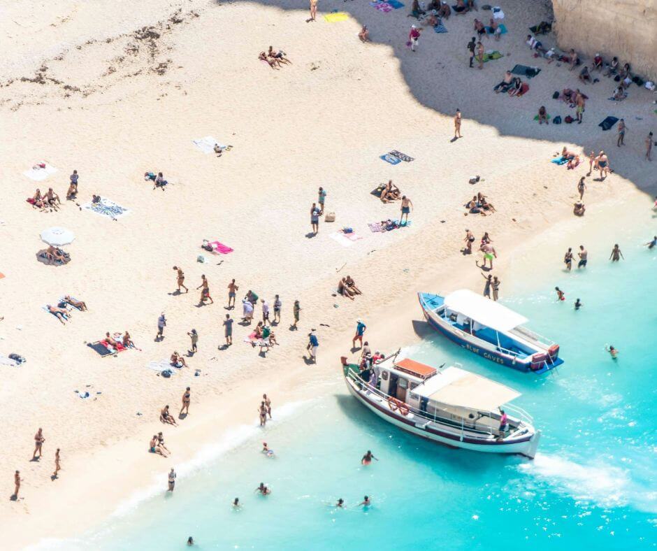 Ein Strand mit vielen Menschen und Leute fahren ihr Motorboot in Greichenland.