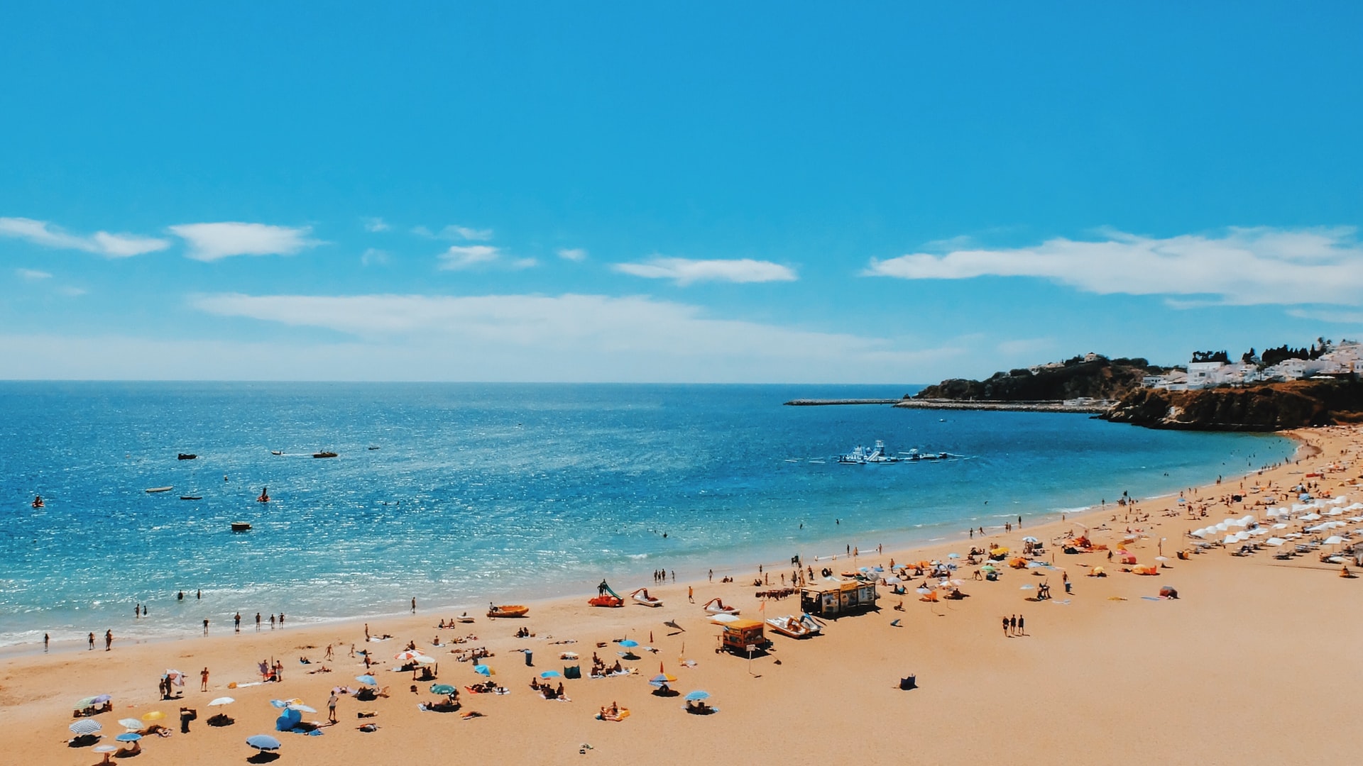 a busy beach that clearly answers the question of "can I travel to portugal?"