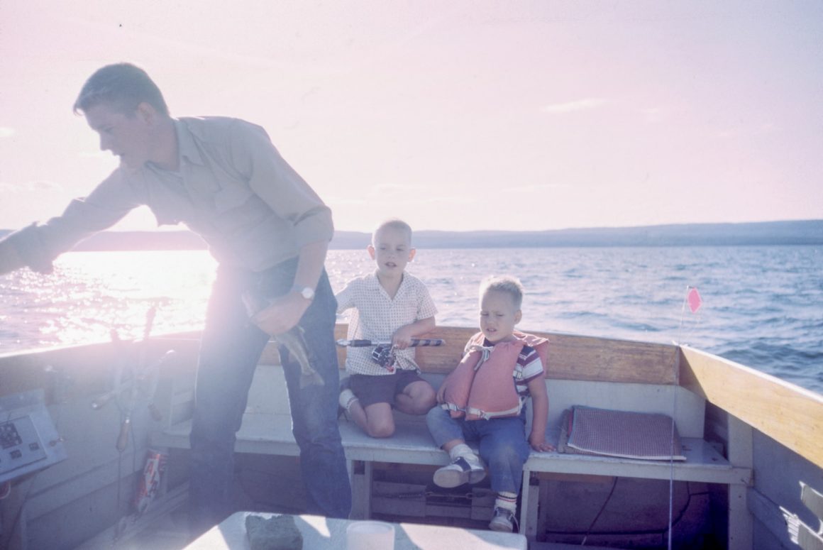 father and 2 children on a boat at sunset