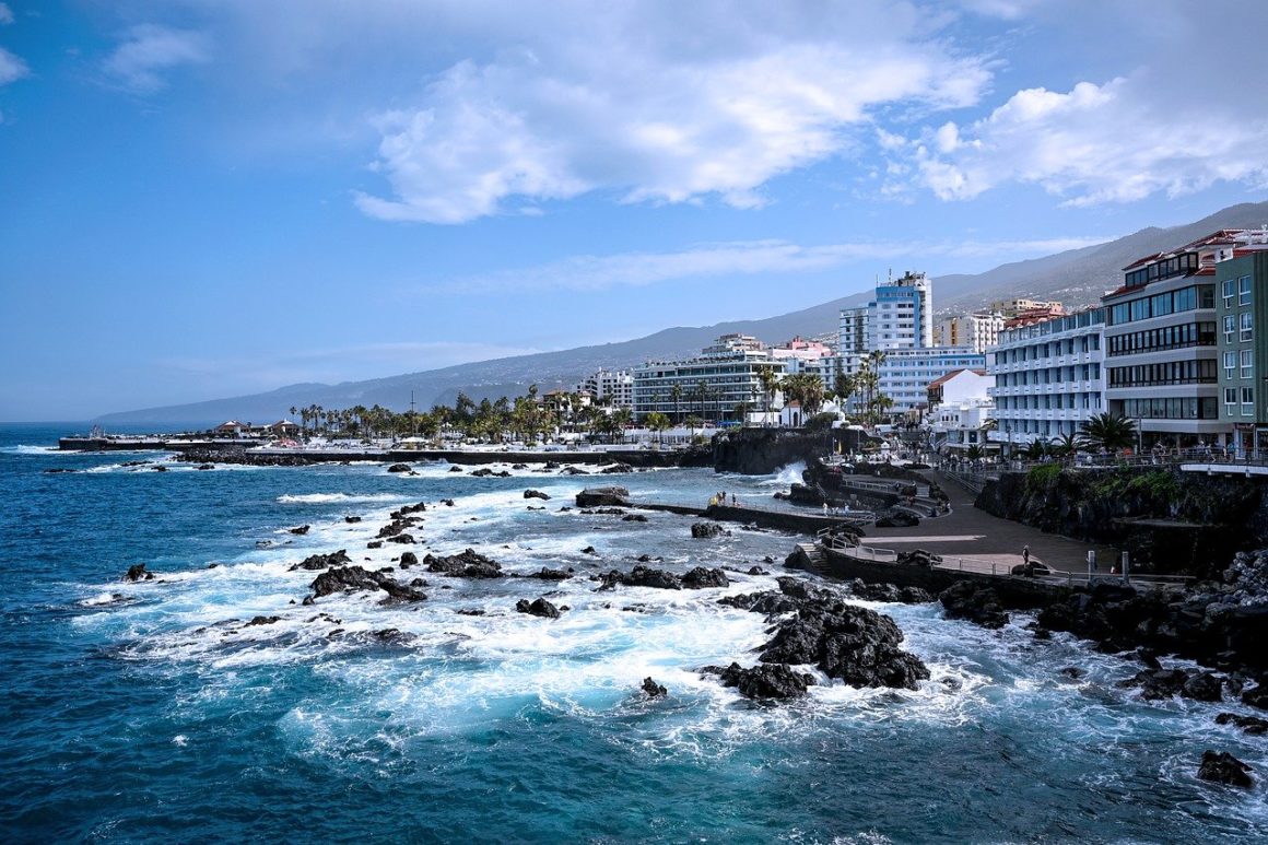 Crystal clear waters, black rocks and sand, bright blue sky