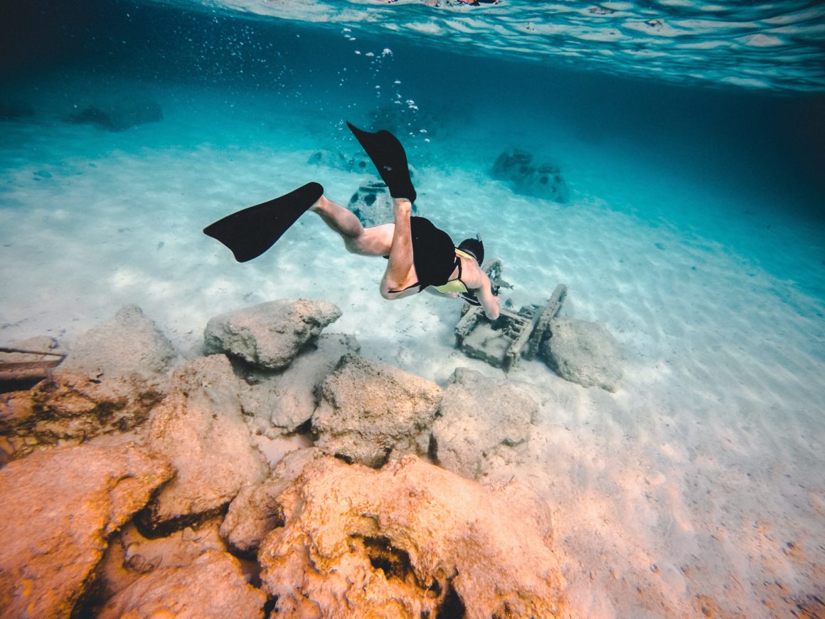 Person scube diving to see the remnants of a shipwreck.