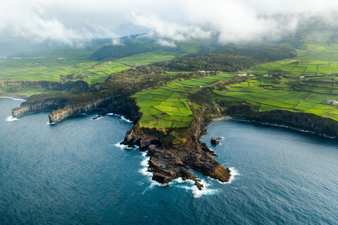 Coastline of the Azores, green fields, rocky cliffs, ocean waves