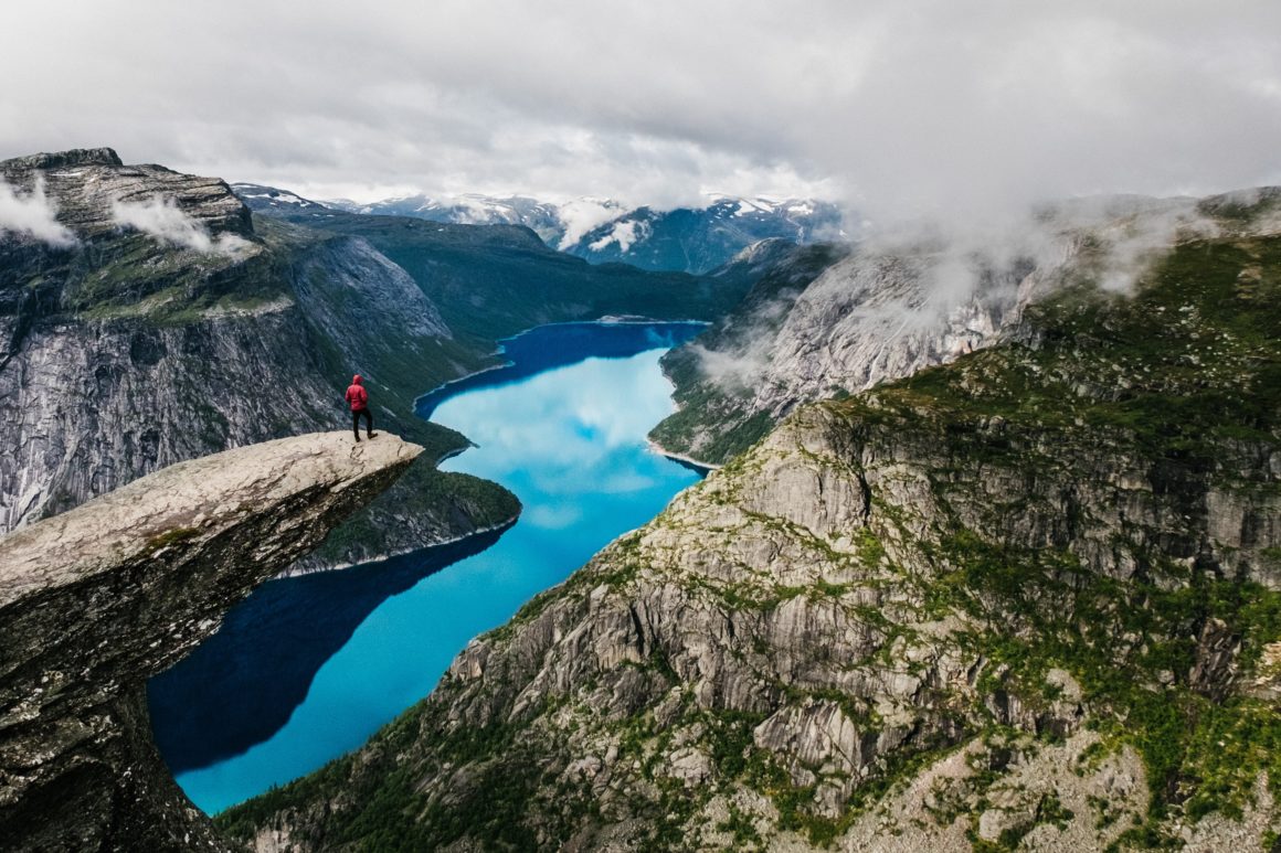 View of a fjord in Norway, hiker standing on the top of cliff