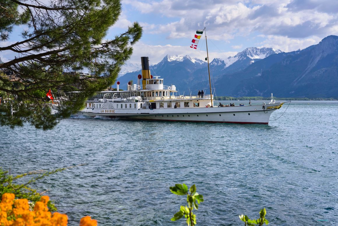 A large boat navigating the waters of Lake Geneva, one of the largest lakes in central Europe. Flowers in the foreground and large mountains in the background.
Best Lakes in Europe