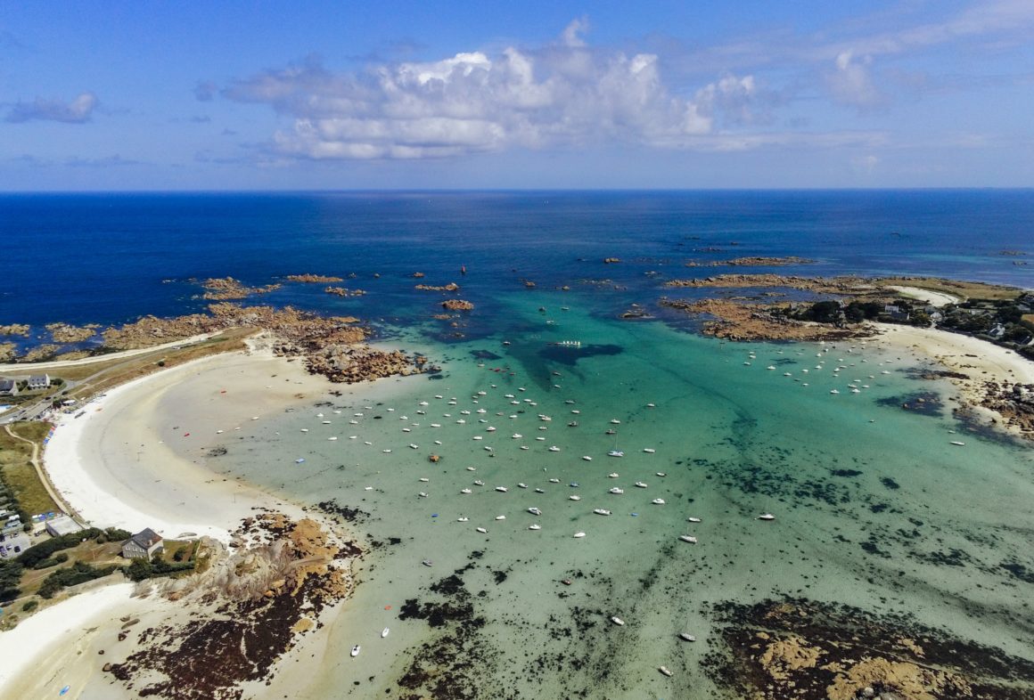 Bird's-eye view of a bay in Brittany. Crystal-clear water, small sailboats.