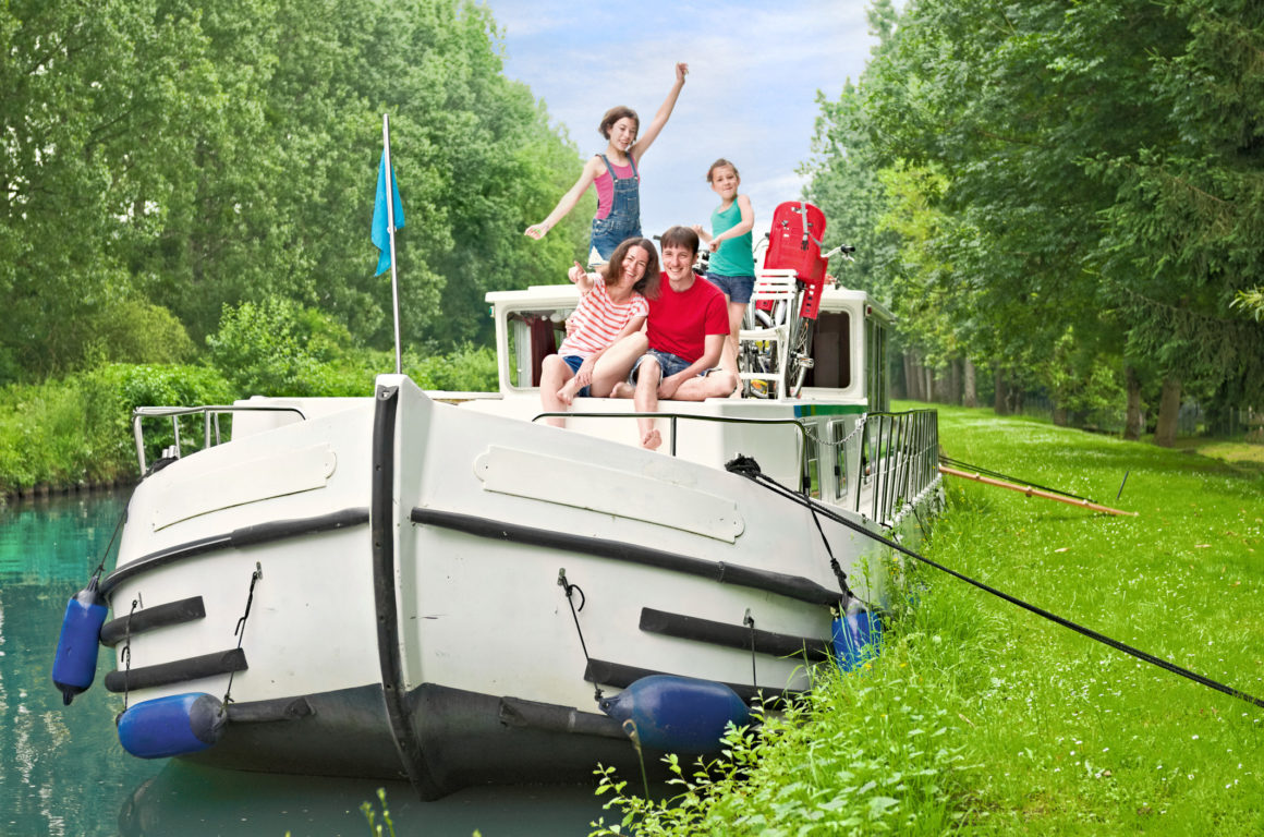 Houseboat, with family on the deck, canal, greenery