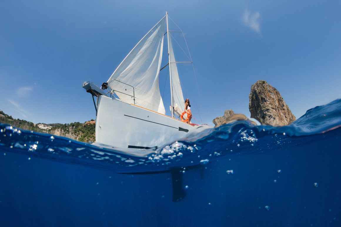 Sailboat, a type of boat propelled by the wind, blue water, cliffs, blue sky