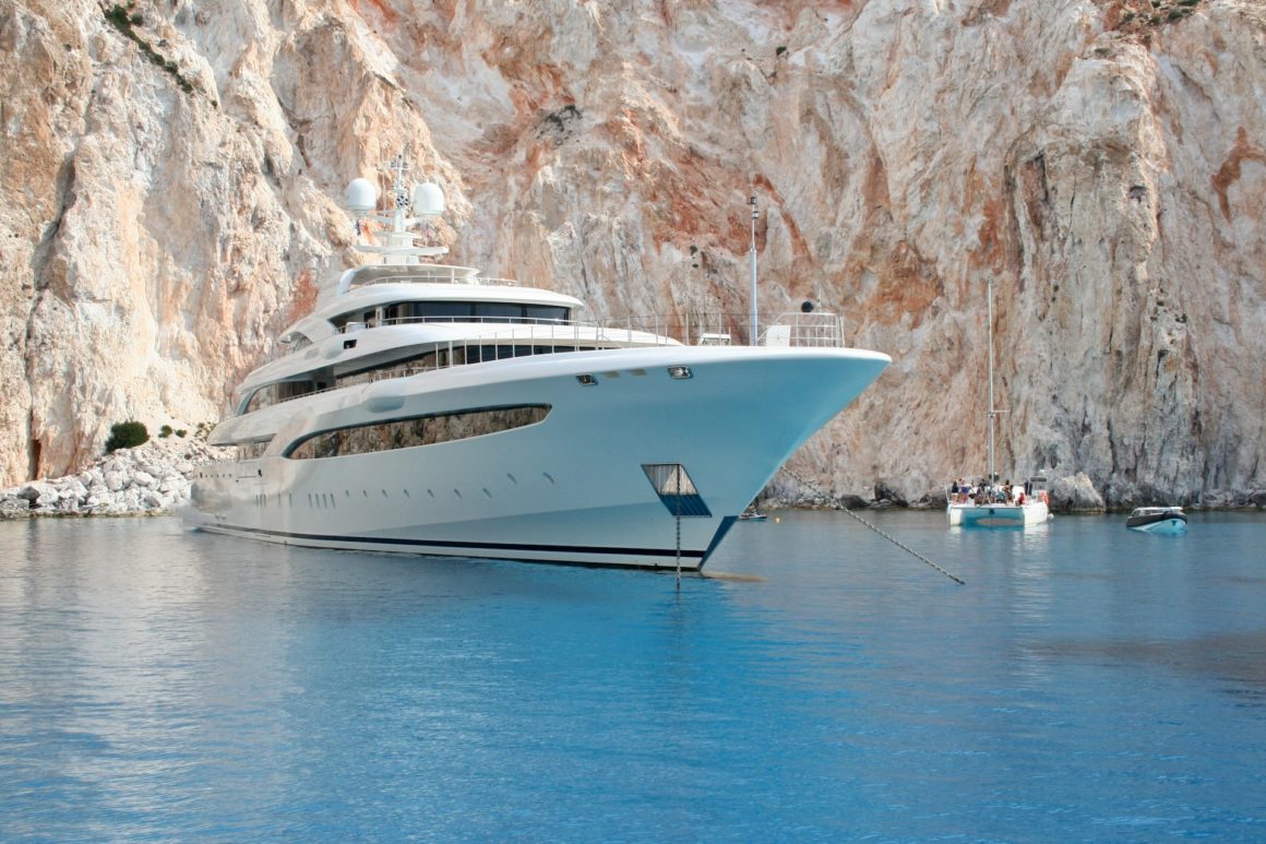 Yacht, blue water, massive white cliffs behind