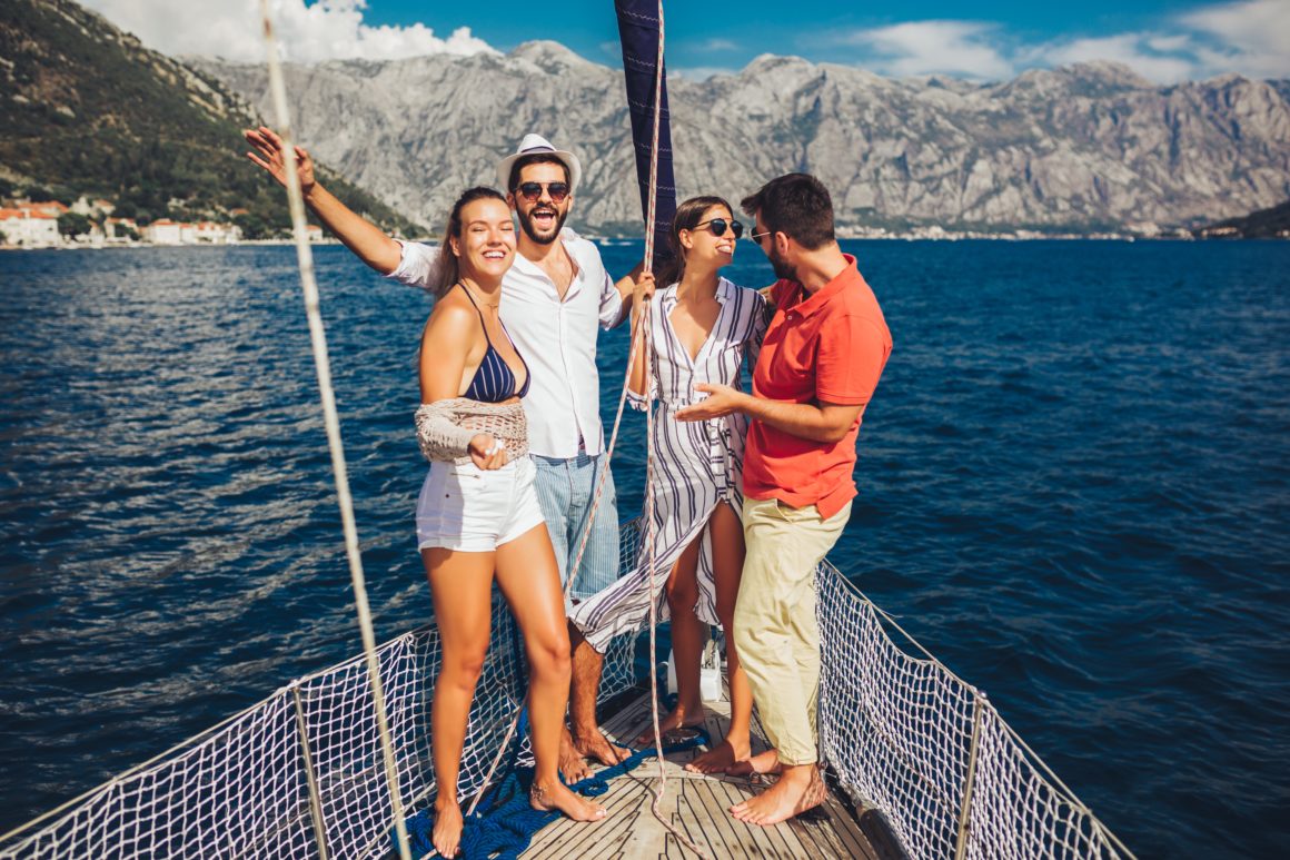 Friends smiling and having fun on a yacht, blue water