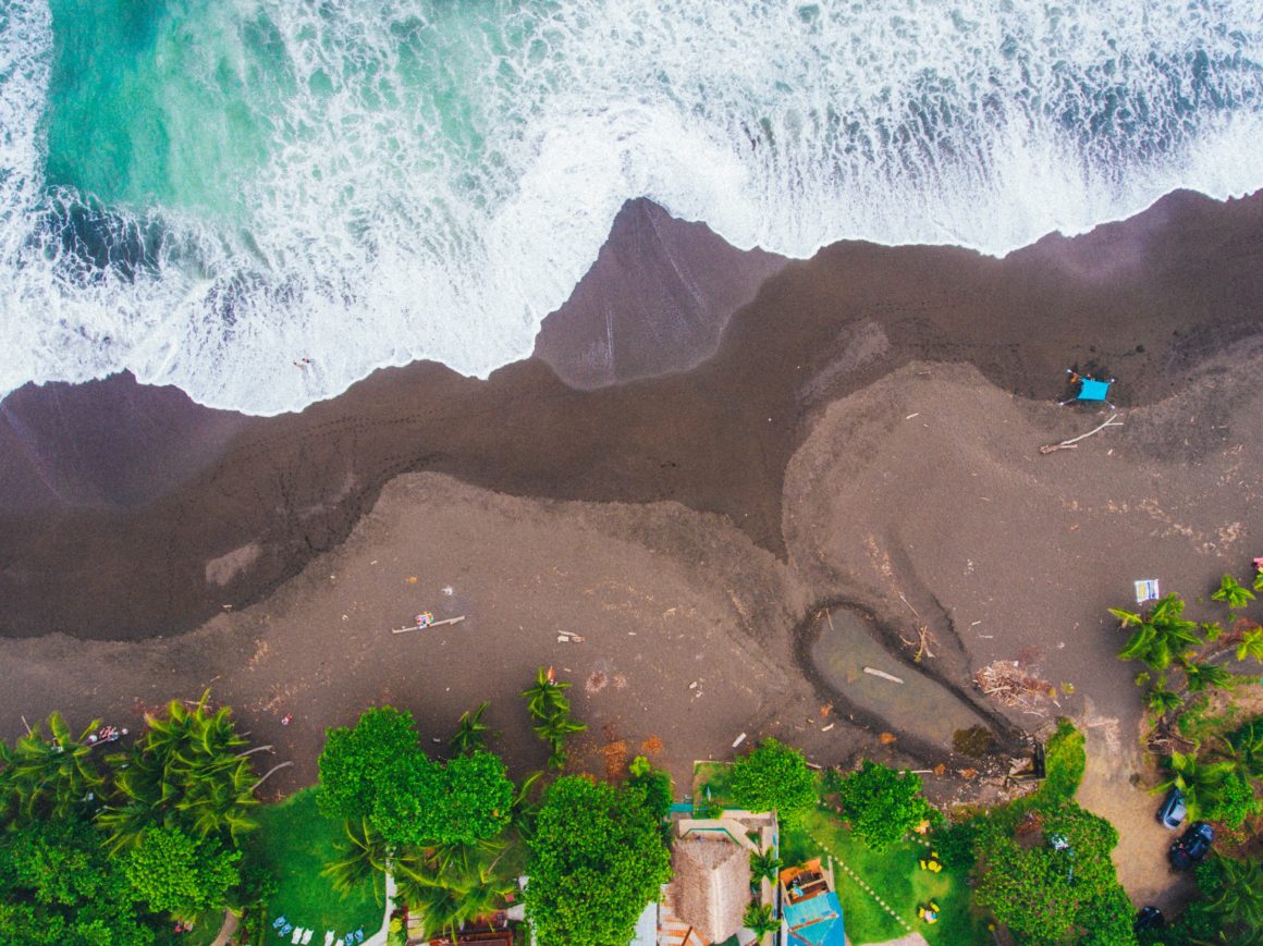 Aerial view of one of the black sand beaches with crashing waves