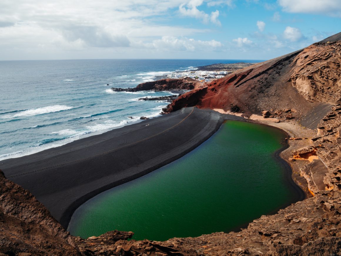 View of one of Lanzarote's black sand beaches, with green lagoon