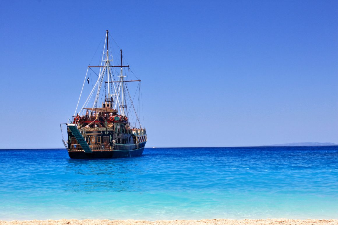 Gulet on stunning blue water with golden sand in the forefront of the picture.