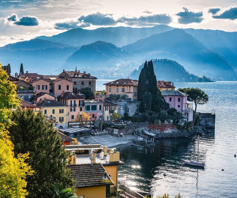 Colorful town on the water in Lake Como with a sailboat