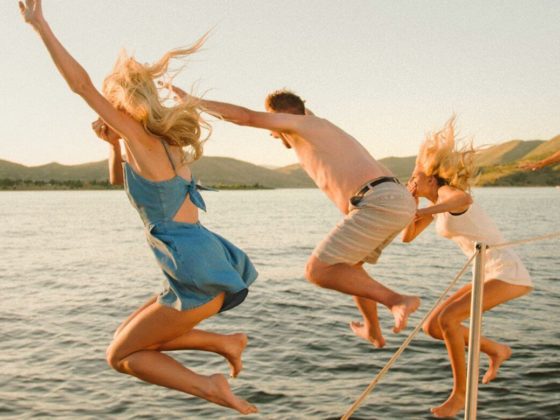 friends jumping from sailboat into the sea