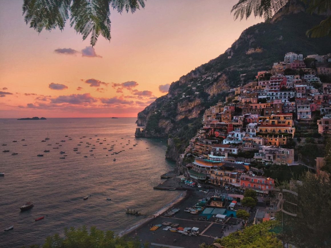 Vibrant pink sunset behind a village perched on a cliff.