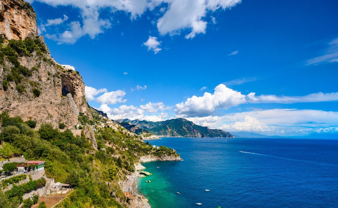 Steep green cliffs of the Amalfi Coast meeting the deep blue sea.