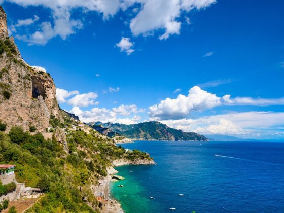Steep green cliffs of the Amalfi Coast meeting the deep blue sea.