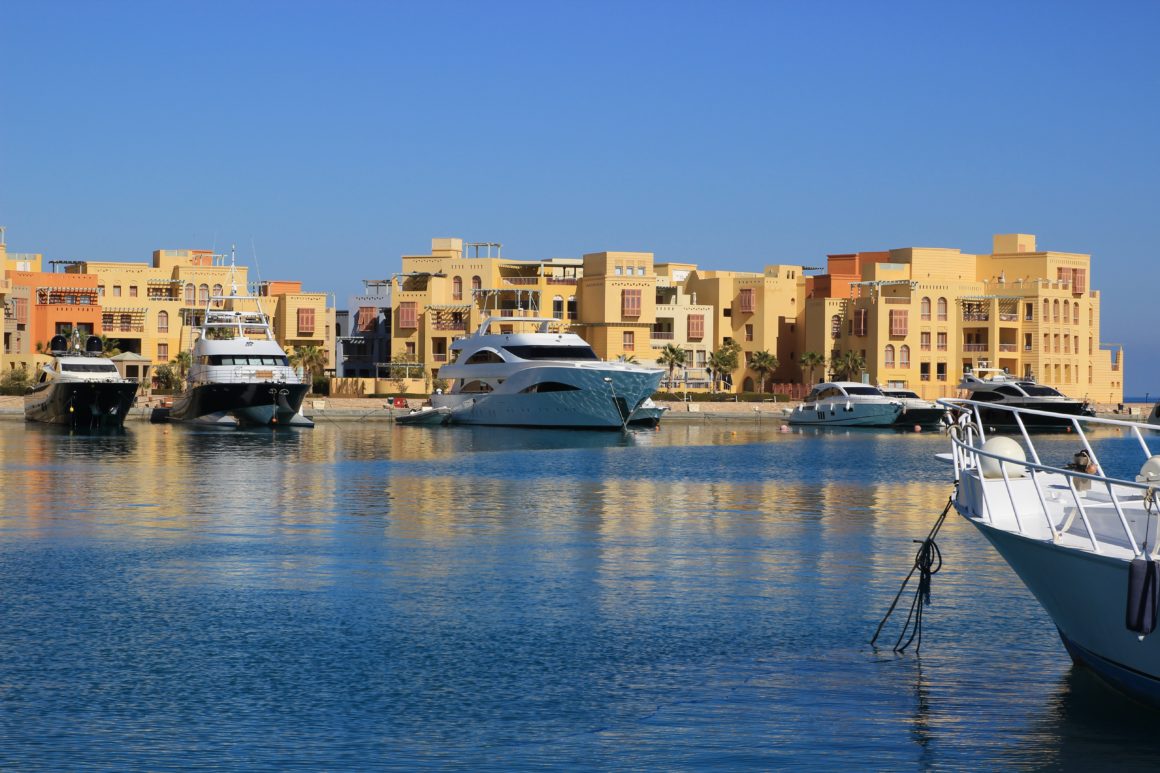 Luxury yachts moored in the marina of El Gouna on the Red Sea, lined with pastel buildings.