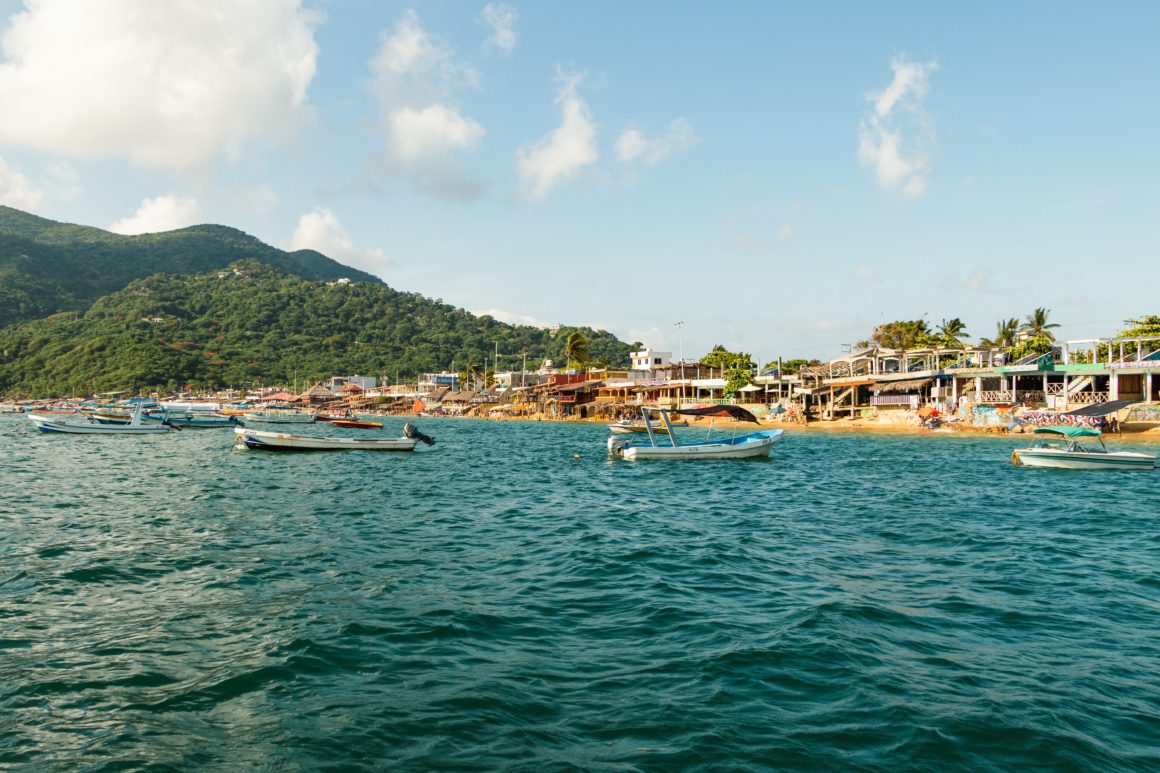 Small fishing boats anchored off a lively seaside village in Mexico