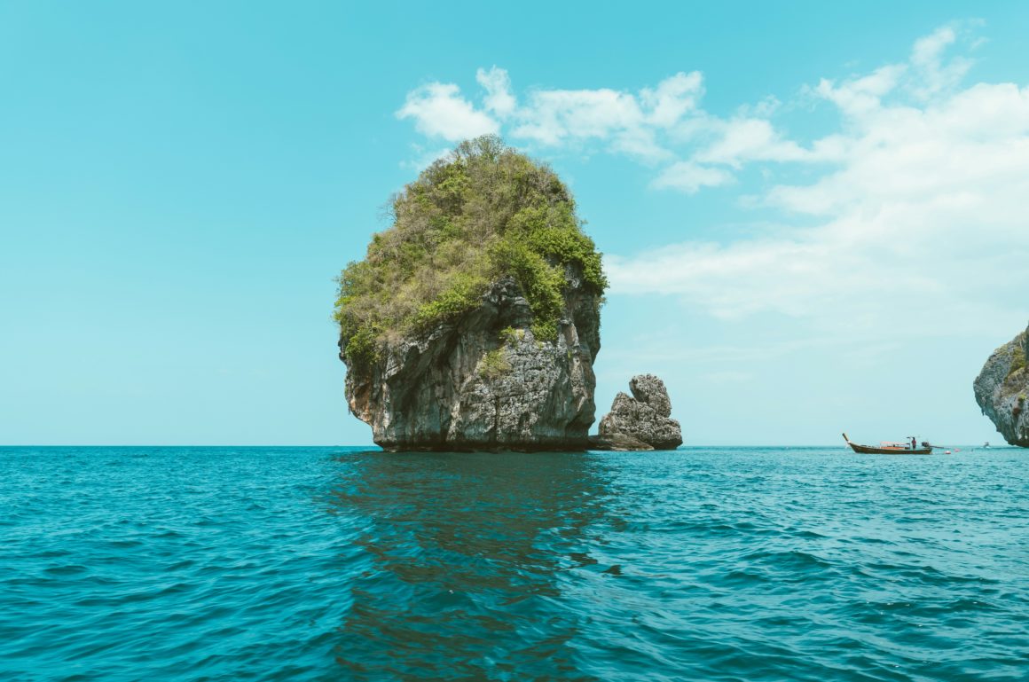 Long-tail boat cruising near a limestone islet in the Phi Phi Islands