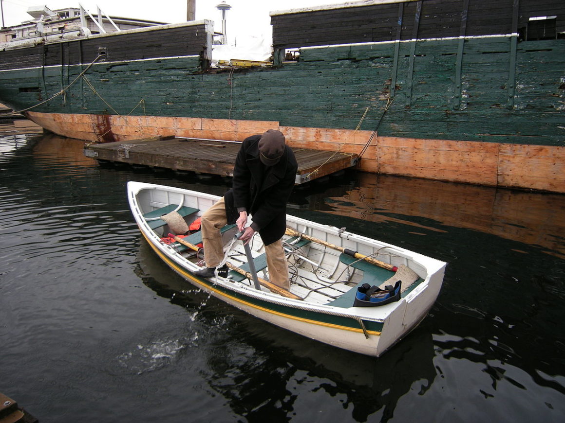Person using a hand pump to remove water from the bilge of a small boat.