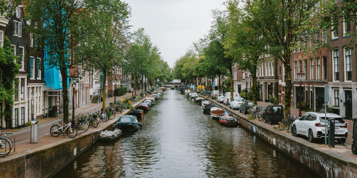 A picturesque canal in Amsterdam lined with trees and boats.