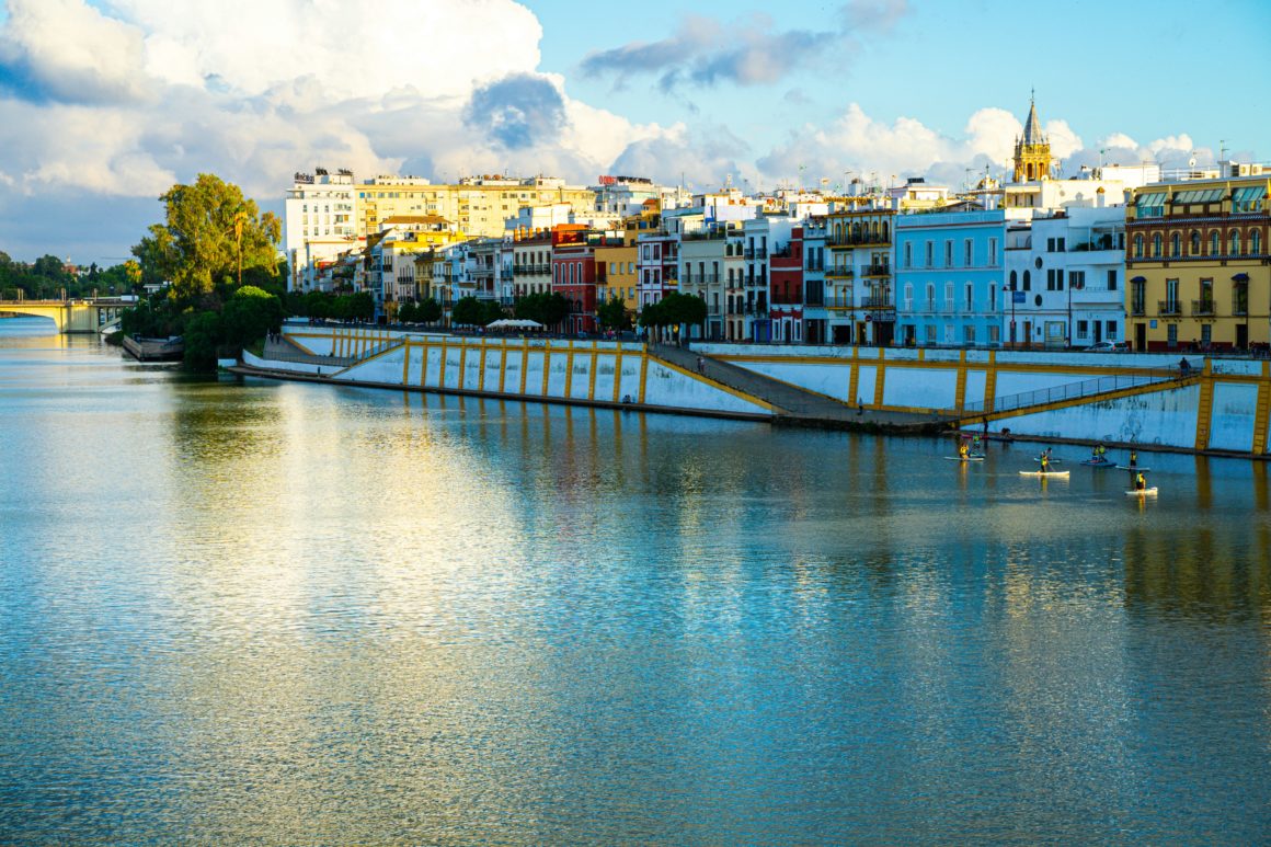 Paddleboarding past the colorful Triana district on the Guadalquivir River, Seville.