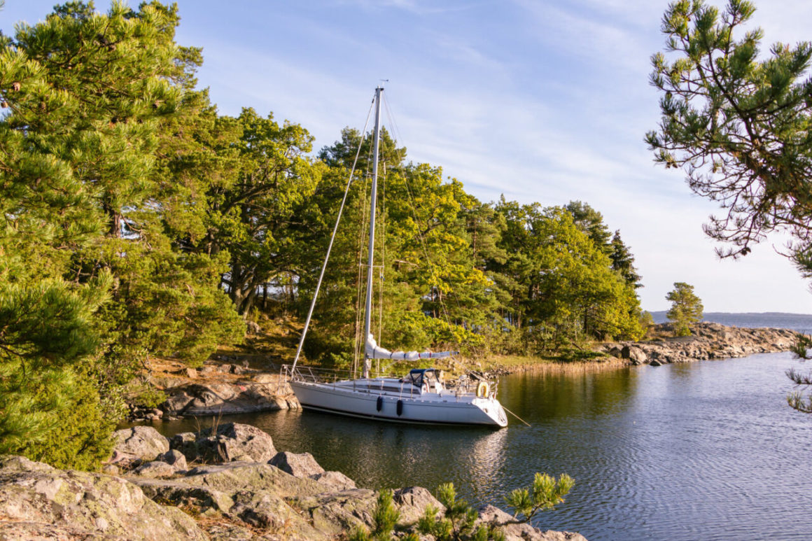 Sailboat anchored in a rocky cove.