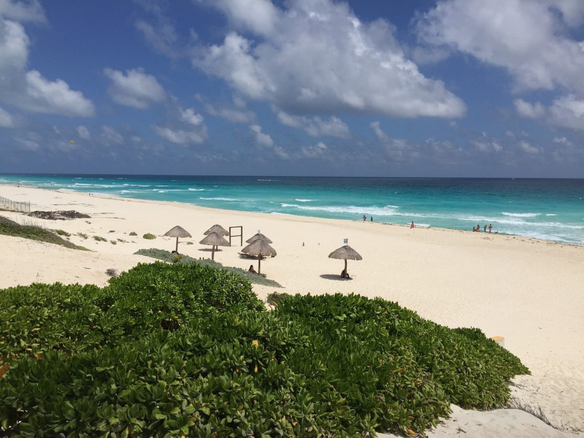 Playa de los delfines en Cancún. Extensa playa sin edificios de agua turquesa con un poco de oleaje.