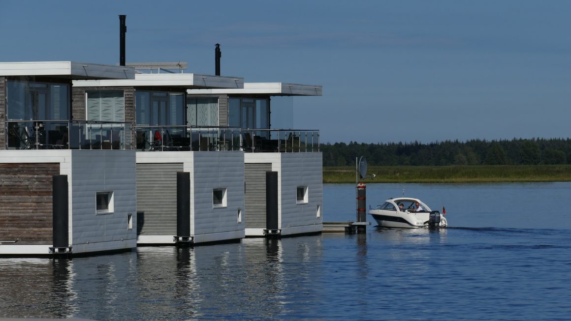 Tres casas flotantes, otro tipo de barco a motor, amarradas en un lago.