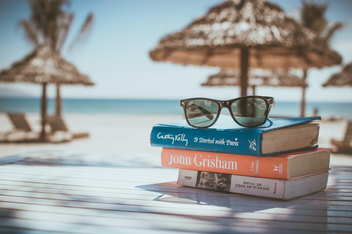 Gafas de sol sobre una pila de libros sobre una mesa en la playa en un viaje de último minuto