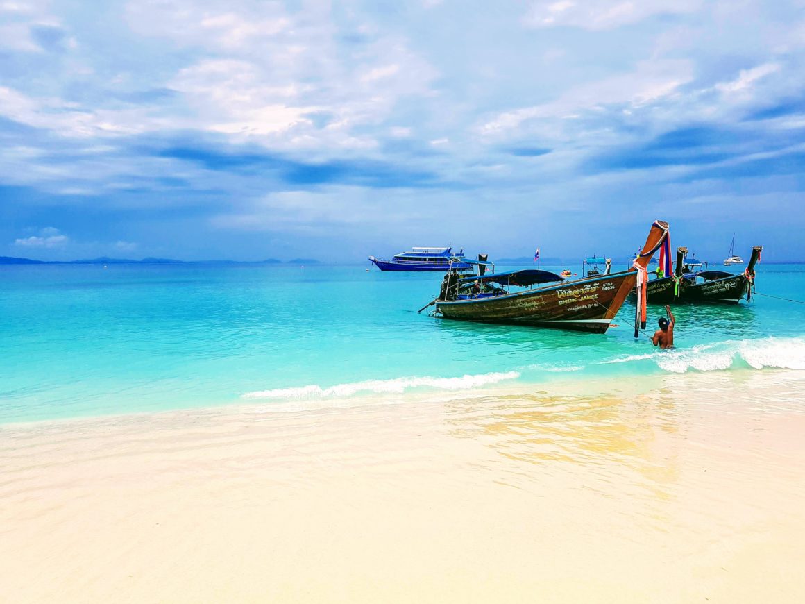 Imagen de una playa de Tailandia con un par de botes de madera en la orilla