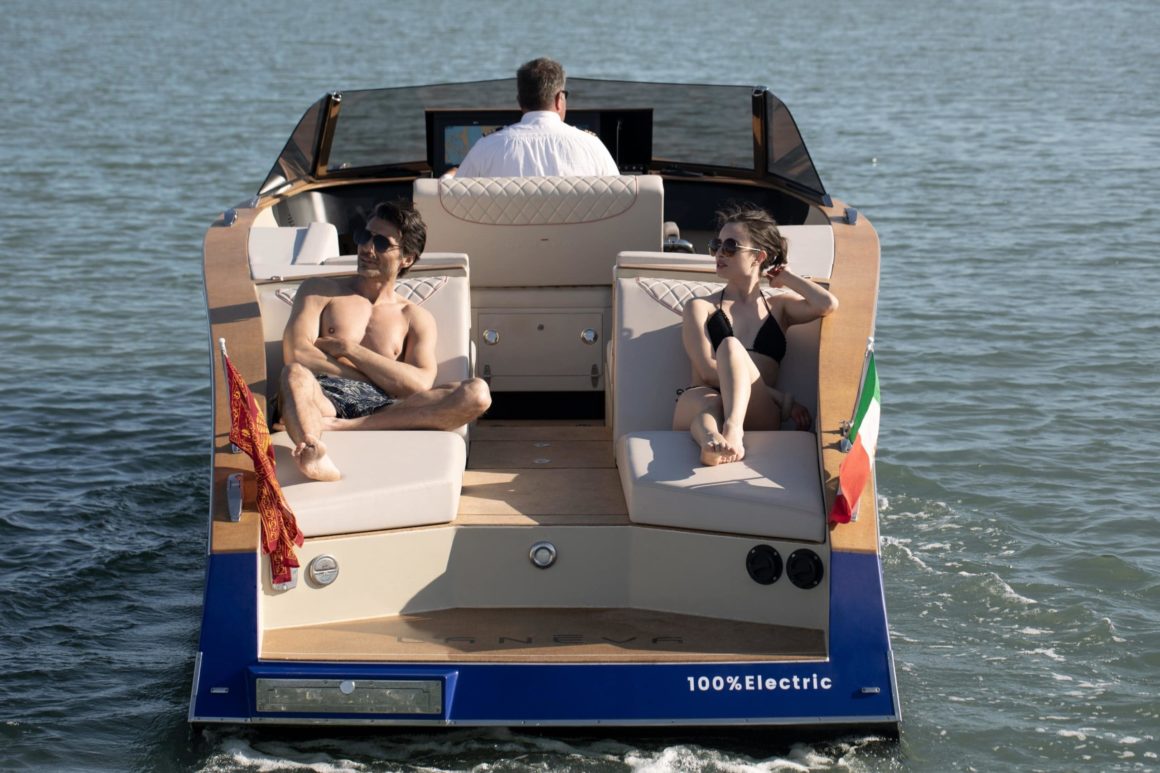 Un patrón junto a dos personas tomando el sol en un barco eléctrico
