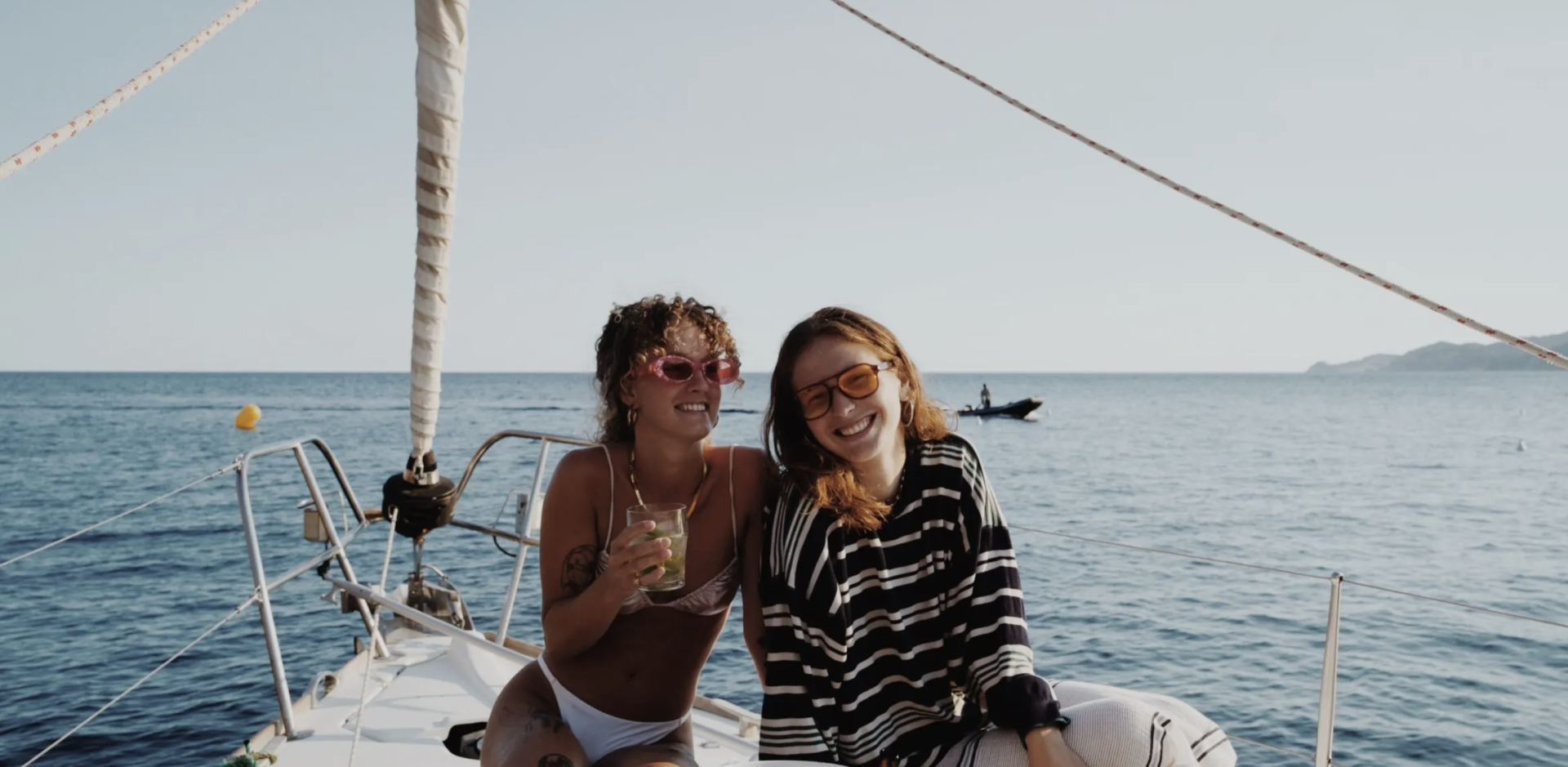 Dos chicas en un barco tomando bebidas riéndose