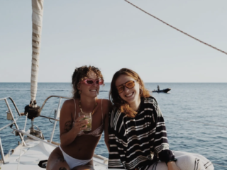 Dos chicas en un barco tomando bebidas riéndose
