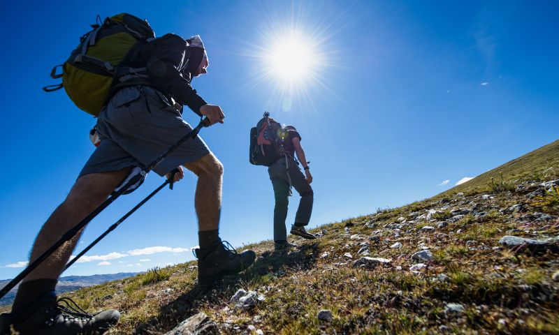 Sole, cielo azzurro, montagna, due persone fanno trekking