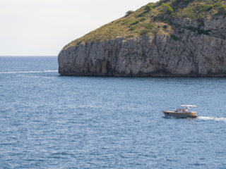 Veduta su barca a motore e falesie