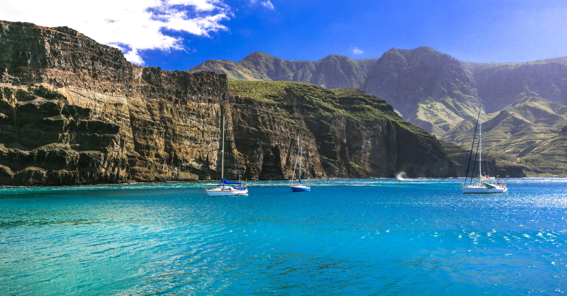 Barche a vela mare turchese scogliere Canarie.